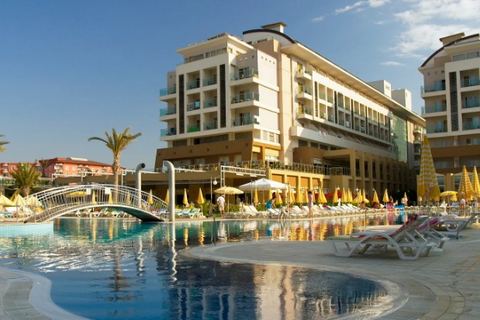 Hotel de varias plantas con la piscina exterior, las hamacas y las sombrillas abiertas en plena temporada