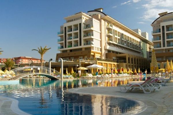 Hotel de varias plantas con la piscina exterior, las hamacas y las sombrillas abiertas en plena temporada
